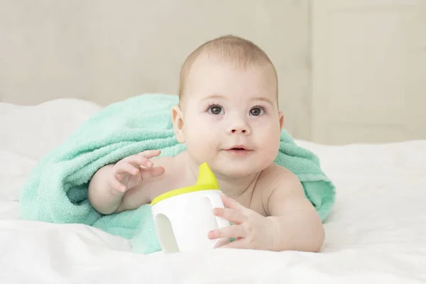 Meisje jongen gewikkeld in een handdoek met een non-morsbeker. Kaukasisch baby portret zachte focus — Stockfoto