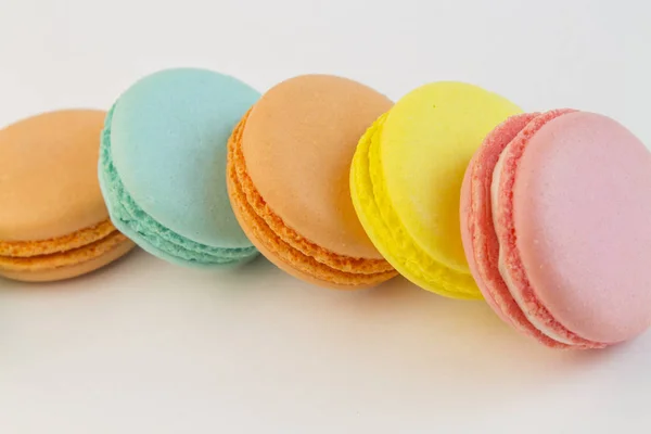 Bolinhos de massa franceses cupcake macarons close-up. Macaroons multi cor em um fundo branco, amarelo rosa macaronis azul — Fotografia de Stock