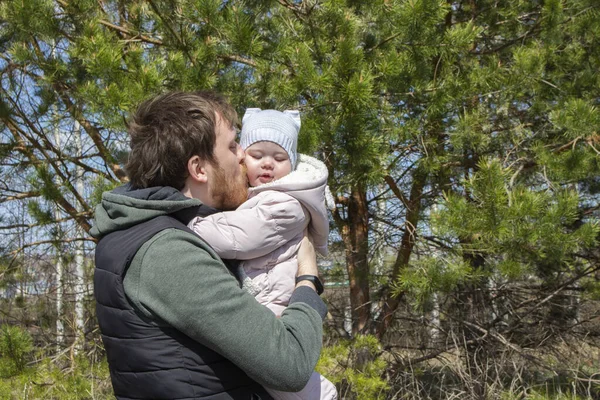 Молодой отец целует новорожденную дочь, гуляет по парку, отец с маленькой девочкой нежность любви ухода — стоковое фото