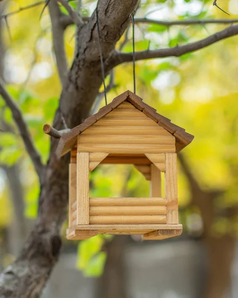 Wooden homemade house hanging on a tree, bird feeder. Small log house for feeding small birds in winter — ストック写真