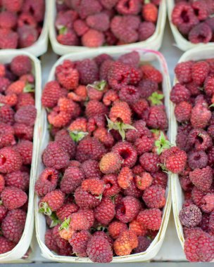 Tahta kutuda taze ahududu, yiyecek arka planı dikey. Çiftçi pazarının tezgahında ahududu, bir sürü dut.