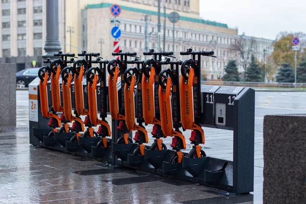12-10-2019, Moskova, Rusya. 12-10-2019, Moskova, Rusya. Ulaşım ve spor aletleri için şehir kirası, kiralık scooterlı otomatik bir raf. Turuncu mobiletler katlı, yağmurlu havada asılı