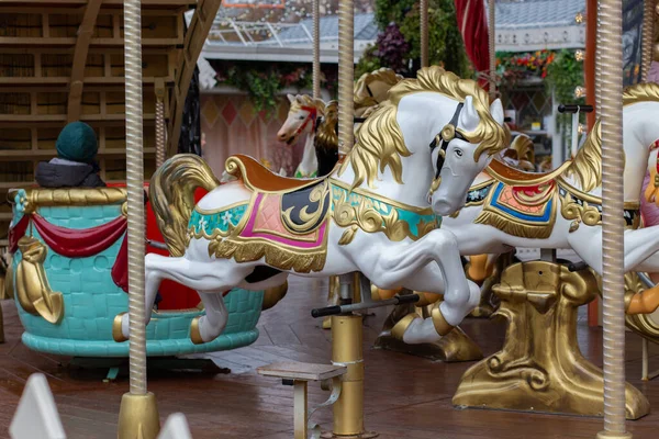 Slavnostní kolotoč s krásnými světlými koňmi. Zábavní park ve městě, vánoční zábava — Stock fotografie