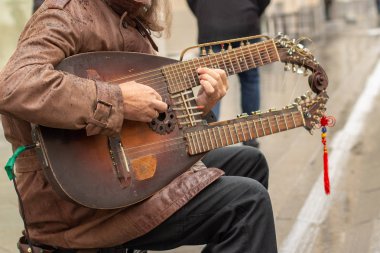 12-10-2019, Moscow, Russia. Unusual musical instrument in the hands of a street musician. A guitar with two necks sounds like a guitar, gusli, sitar, lyre.