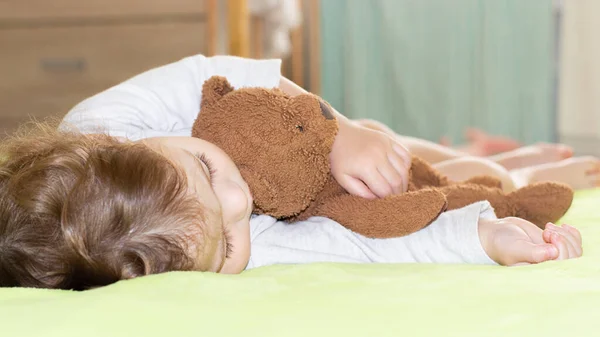 Garota caucasiana menino 1 ano de idade dormindo formigamento urso de pelúcia marrom. O topo de um bebê adormecido — Fotografia de Stock