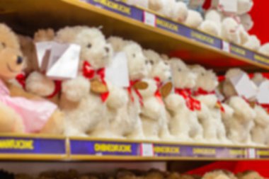 Arka plan, oyuncak dükkanında beyaz oyuncak ayılarla dolu raflar. Çocuk oyuncakları ile bulanık arkaplan