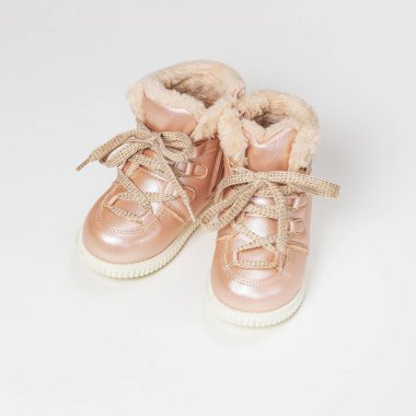 Kürklü küçük pembe deri kış botları. Beyaz arka planda sıcak bebek ayakkabıları..
