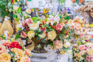 Koyu metal bir vazoda ev dekorasyonu için zarif bir buket gül. İç dekorasyon, kartpostal tasarımı. Yapay çiçekler yeşil yapraklı zambak dalı, romantik kart