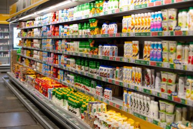 Moskova, Rusya - 23 Ağustos 2020: Bir süpermarkette süt ürünleri rafı. Ekşi kremalı, yoğurtlu, süzme peynirli ve sütlü çok renkli kavanozlar. Mallarla dolu büyük buzdolabı.