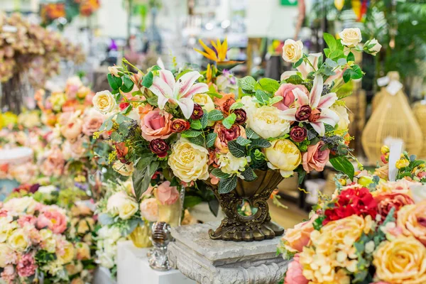 Yapay çiçekli ev dekoru, gül zambağı yaprakları. Ev dekorasyonu için zarif bir buket, koyu metal bir vazoda sarı gül. İç dekorasyon, kartpostal tasarımı ögesi