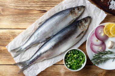 Eski ahşap masada kırmızı soğan, limon ve baharatile tuzlu ringa balığı.