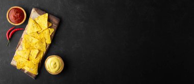 Siyah arka plan üzerinde salsa ve peynir sosu ile Geleneksel Meksika gıda mısır cipsi nachos. Banner biçimi. Kopyalama alanı ile üstte görünüm.