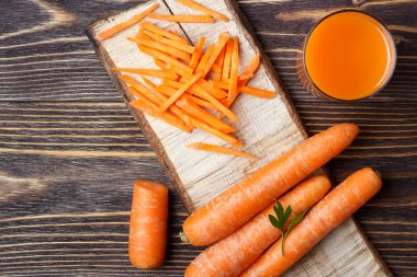 Ahşap arka planda dilimlenmiş havuç ve havuç suyu.