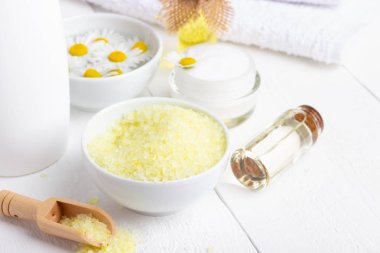 Beyaz ahşap masa üzerinde banyo sarı deniz tuzu, doğal krem ve papatya ile Spa arka plan
