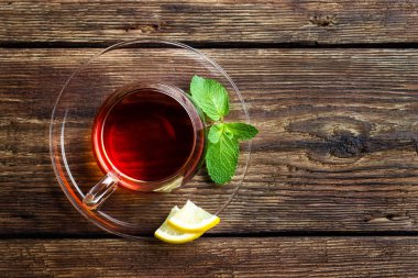 Ahşap rustik arka plan üzerinde çay, nane ve limon ile Cam fincan. Kopyalama alanı ile üstte görünüm.