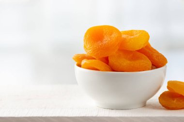 Hafif ahşap arka plan üzerinde bir kapta kuru kayısı.