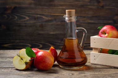 Elma sirkesi ve ahşap bir arka plan üzerinde taze kırmızı elma