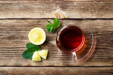 Ahşap rustik arka plan üzerinde çay, nane ve limon ile Cam fincan. Kopyalama alanı ile üstte görünüm.