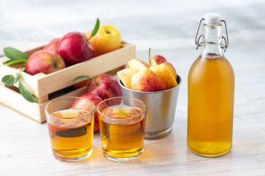Sağlıklı organik gıda. Elma sirkesi veya meyve suyu cam şişe ve hafif bir arka plan üzerinde taze kırmızı elma.