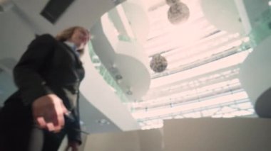 İki iş adamının tokalaşması. Bir iş adamı ve bir kadın büyük ve çok katlı bir ofis lobisinde takım elbise giyiyor. Çatı penceresindeki güneşin parlaklığı