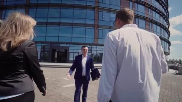 Бизнесмен рассказывает своим коллегам кое-что важное возле офисного здания — стоковое видео