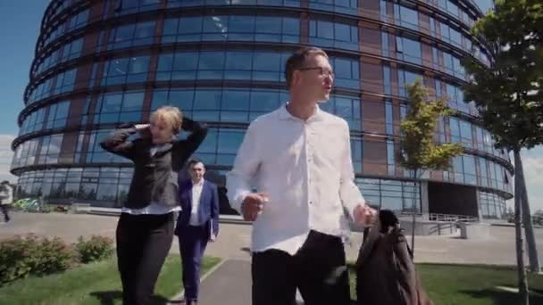 Three businessmen go, laugh and dance cheerfully in front of the office building — Stock Video