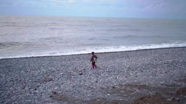 Bir çocuk sahilde dondurma yer.