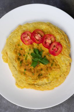 Tabakta servis edilen domates dilimleri, kişniş ve soğanlı omlet
