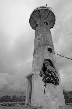 Bulutlu bir günde eski deniz feneri ya da kulesi olan kadın, siyah beyaz fotoğraf