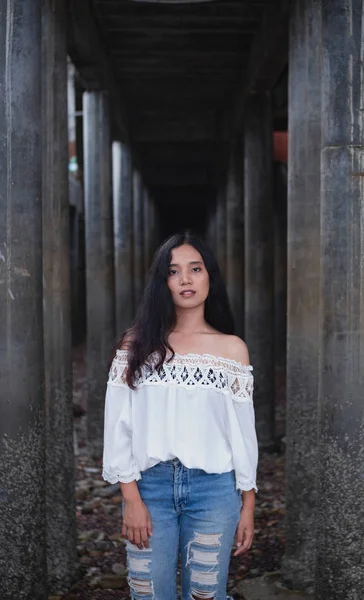 asian woman in top with open shoulders posing at camera