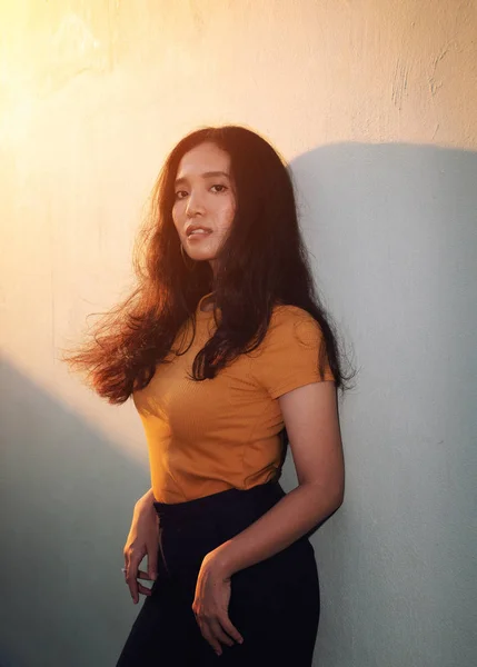 young woman in orange t shirt posing in evening sunlight