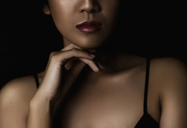 cropped shot of young woman with glossy skin on dark background