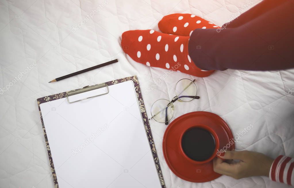 feet in red polka dot socks and red coffee cup on bed