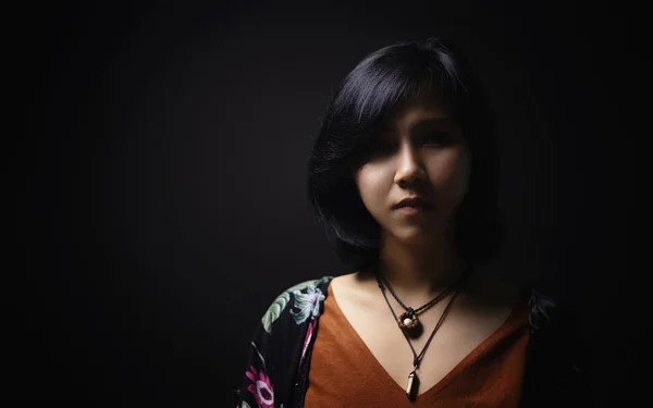 亚洲短黑头发的女人 穿着皮革和石头制成的珠宝在她的脸上 有一个小雀斑在黑色的背景和阴影 — 图库照片
