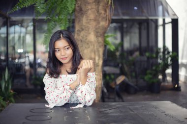 Beyaz bir elbise giyen güzel bir Asyalı kadın, o restoranın gölgeli terasında gülümseyerek oturdu. Mutlu bir şekilde düşünüp gidiyordu..