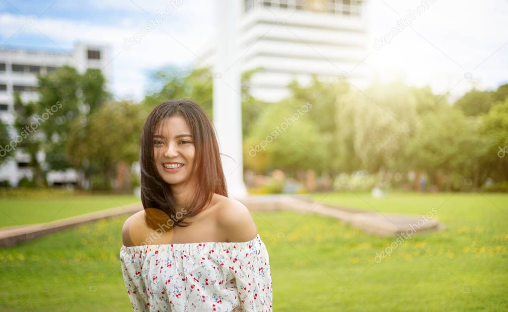 A beautiful Japanese woman wearing a white dress, walking happily in the green lawn. In the light of the sun