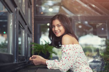 Beyaz bir elbise giyen güzel bir Asyalı kadın, o restoranın gölgeli terasında gülümseyerek oturdu. Mutlu bir şekilde düşünüp gidiyordu..