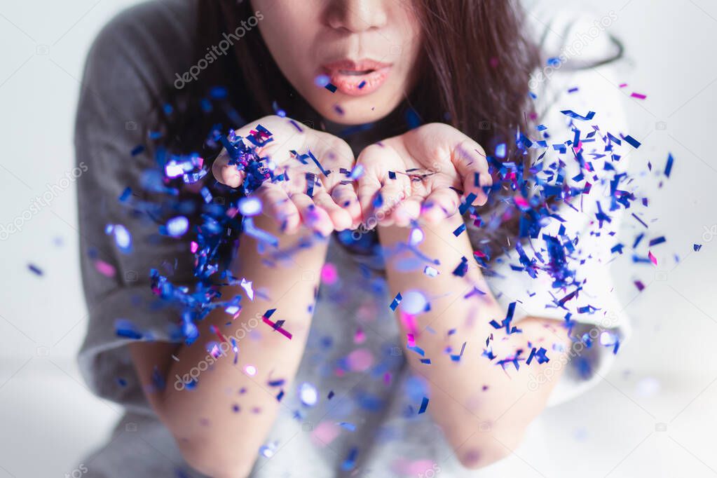 The woman who is blowing the glitter blue and fuchsia On a white background and bright light