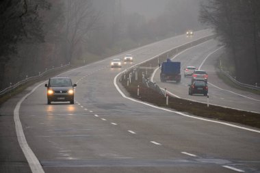 Arabalar sis. Kötü kış hava ve yolda tehlikeli otomobil trafik. Sisli gün hafif araçlar.