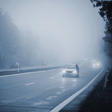 Arabalar sis. Kötü kış hava ve yolda tehlikeli otomobil trafik. Sisli gün hafif araçlar.