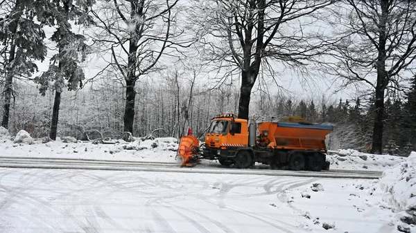 Front view of snowplow service truck - gritter car spreading salt on the road. Maintenance of roads in winter in the mountains.