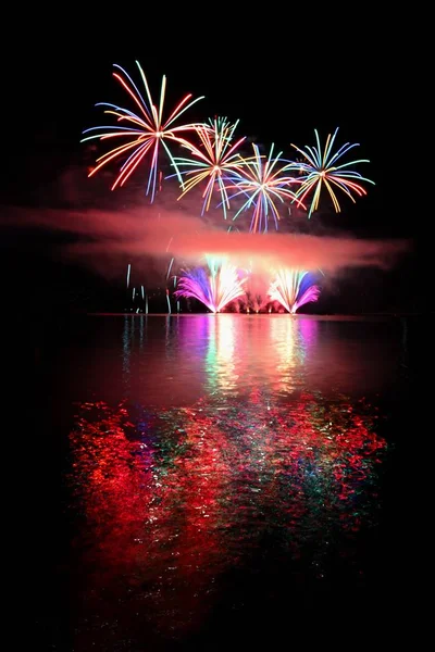 Beautiful colorful fireworks on the water surface. Night scene. Concept for holidays and celebrations. — Stock Photo, Image