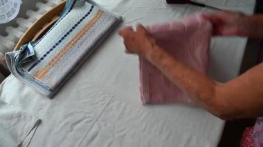 Yaşlı bir kadın eski bir ütüyle giysileri ütülüyor ve onları evde katlıyor. Ev işleri ve retro konsept.