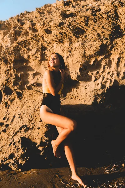 Chica en traje de baño disfrutando y caminando en la playa, en verano, en la puesta de sol. Retrato de una joven feliz sonriendo al mar . — Foto de Stock