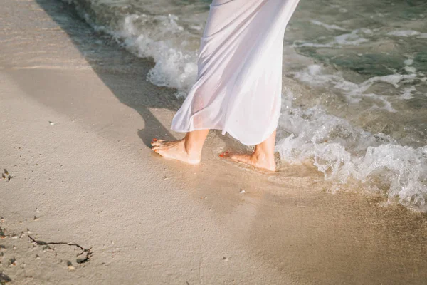 Η νύφη περπατά στην παραλία ξυπόλητη πατώντας στο νερό — Φωτογραφία Αρχείου