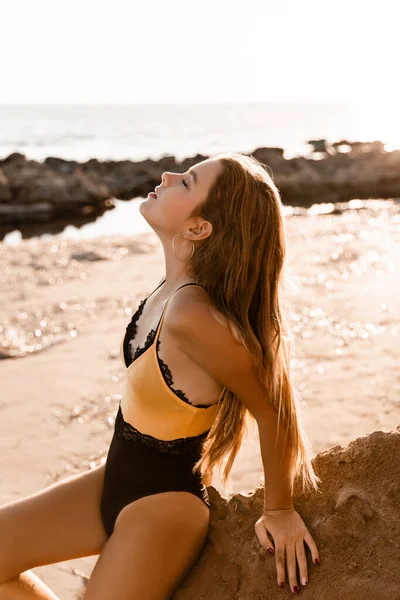 Chica en traje de baño disfrutando y caminando en la playa, en verano, en la puesta de sol. Retrato de una joven feliz sonriendo al mar . — Foto de Stock