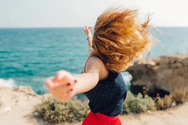 女の子は海の隣を歩く。バックビュー。海で風を。風の中で毛が発達し — ストック写真
