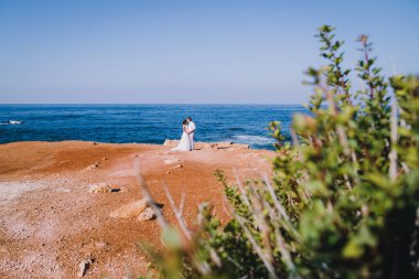 Arka plan, okyanusun önündeki kayalıklarda duran evli bir çift. Sadece arkadan evlilik manzarası. Denizde balayı.