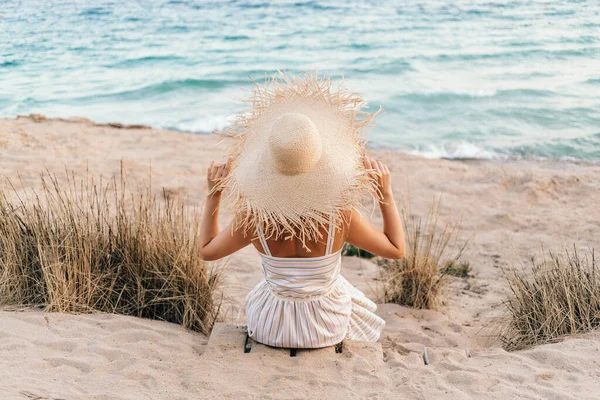 Κορίτσι κρατά το καπέλο με τα χέρια και κοιτάζει τη θάλασσα — Φωτογραφία Αρχείου