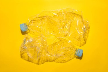 Geri dönüşüm için kullanılan plastik şişeler, sarı arka planda, kopyalama alanı olan kavramsal resim